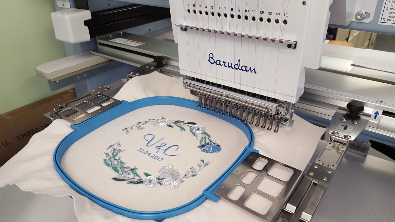 A Barudan embroidery machine stitching a design held in a hoop
